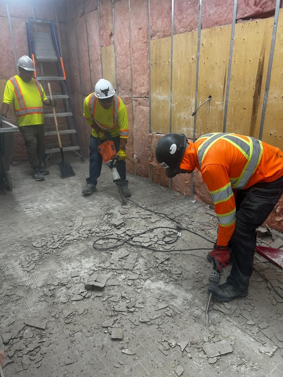 JQUE crew in high-visibility PPE removing flooring during interior demolition at Walmart Sarnia